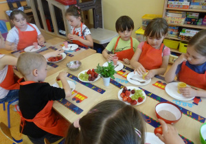 Dzieci nakładają owoce do wafelków.